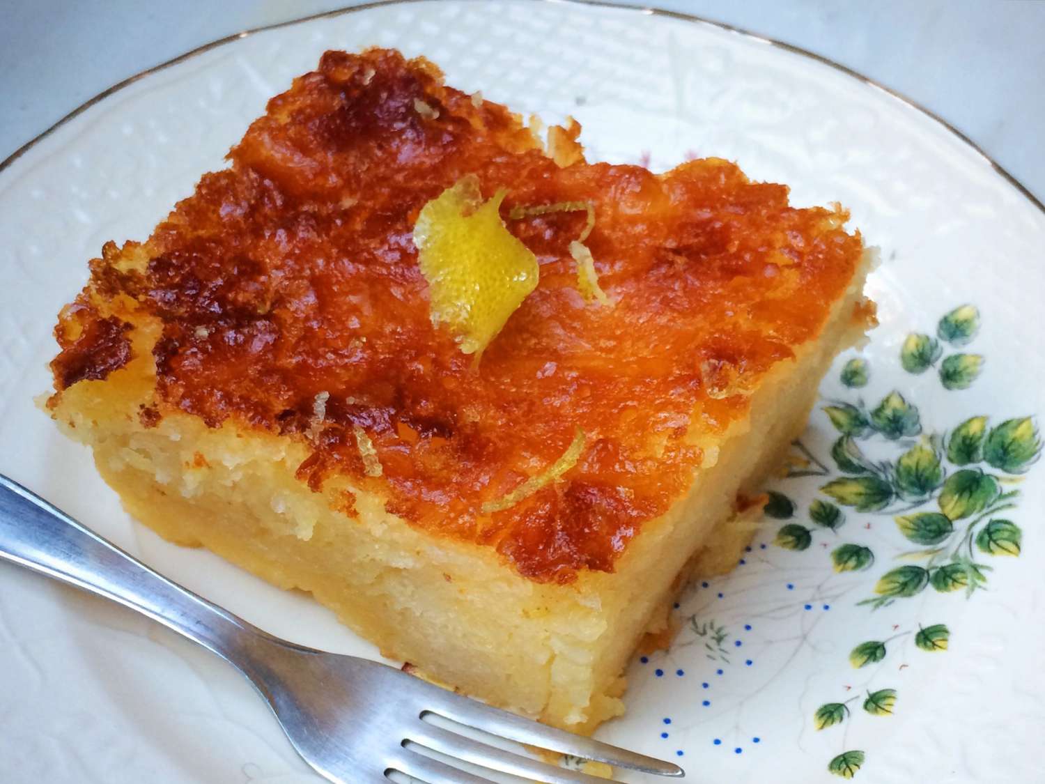 Golden lemon syrup cake on a decorative plate